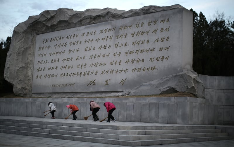 2015년 12월, 평양에서 북한 여학생들이 고(故) 김일성 주석의 연설문이 새겨진 석조 구조물 앞을 쓸고 있다.