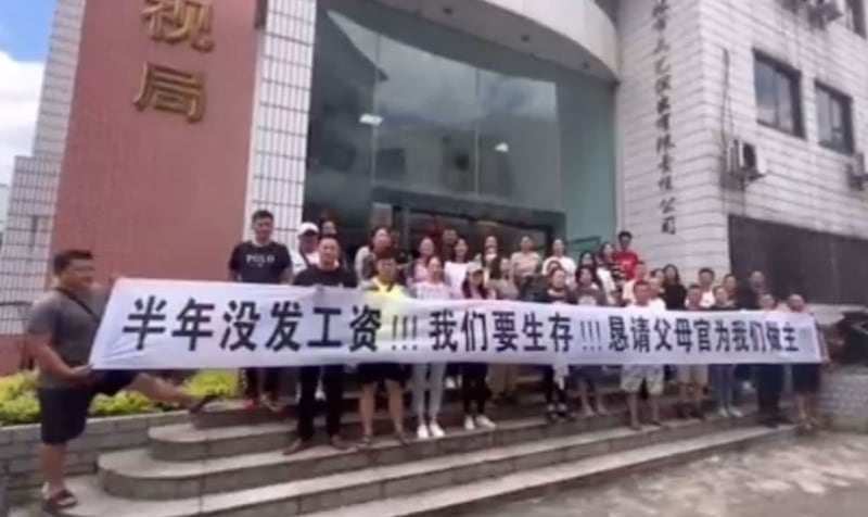 网传视频中,在桂林市广播电视局门前有人拉横幅,声称半年未发工资。9月7日,当局为职工“财务困境”辟谣。(网络视频截图/古亭提供)