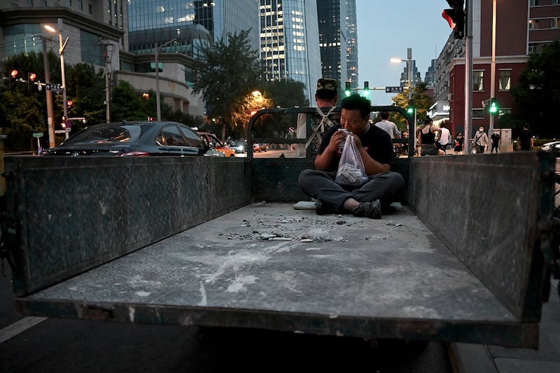 2022年6月21日,北京街头,一名男子在三轮车后座上吃饭。(法新社)