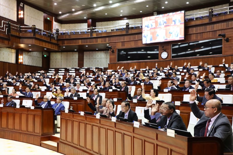 In this photo released by Cambodia's National Assembly, Cambodian lawmakers raise their hands during the session on the draft law on amending the law on nationality at the National Assembly in Phnom Penh, Aug. 25, 2025.