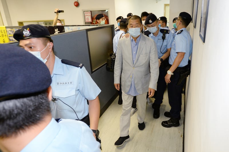 Jimmy Lai is escorted by Hong Kong police officers as they search the office of Apple Daily newspaper on Aug. 10, 2020.