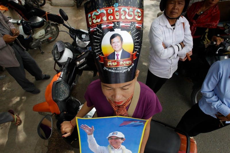 A supporter of the opposition Cambodia National Rescue Party wears a poster of party leader Kem Sokha as she stands outside the Supreme Court in Phnom Penh, Cambodia, Oct. 31, 2017. (Heng Sinith/AP)