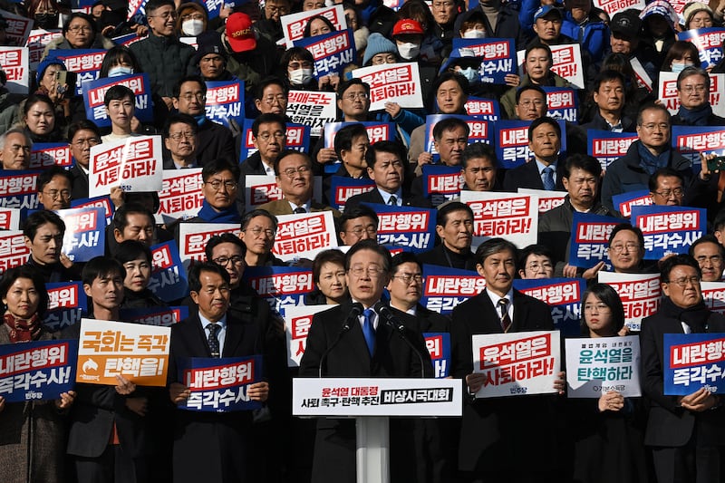 2024年12月4日,南韓國會議員及反對黨民主黨成員舉著寫著「尹錫悅應該辭職!」的標語牌(法新社圖片)