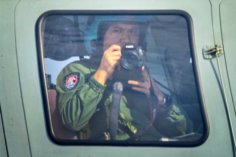 Chinese Navy personnel takes pictures from aboard a helicopter flying close to a Philippine Bureau of Fisheries and Aquatic Resources plane above Scarborough Shoal on February 18, 2025 in the South China Sea.